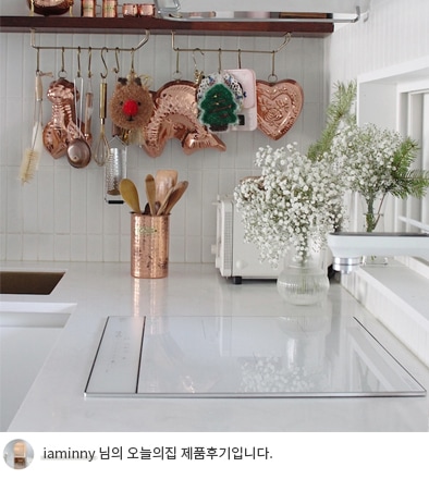 LG 디오스 오브제컬렉션 인덕션 위에 요리 도구들이 정리된 모습. 벽면에 동그란 디자인의 후크에 걸린 다양한 구리색 조리 도구들이 주방 인테리어에 따뜻한 느낌을 더하고 있으며, 하단에는 'iaminny 님의 오늘의집 제품후기입니다.'라는 텍스트가 포함되어 있음.