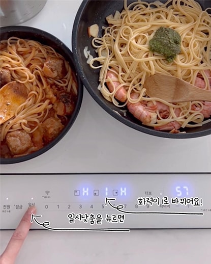 LG 디오스 오브제컬렉션 인덕션에서 요리가 진행 중인 모습. 두 개의 냄비에 파스타와 해산물이 조리되고 있으며, 아래 인덕션 디스플레이에는 '일시낮춤을 뉴르면'와 '화력이 1로 바뀌어요!'라는 텍스트가 표시되어 안전 기능을 설명. 요리와 기능이 돋보이는 장면.