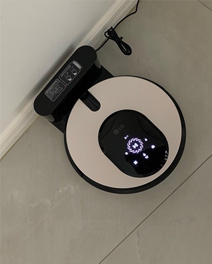 LG 코드제로 오브제컬렉션 M9 로봇청소기가 충전 도크에 배치된 모습. 로봇 상단에 디지털 디스플레이가 작동 중이며 충전 상태를 보여줌.