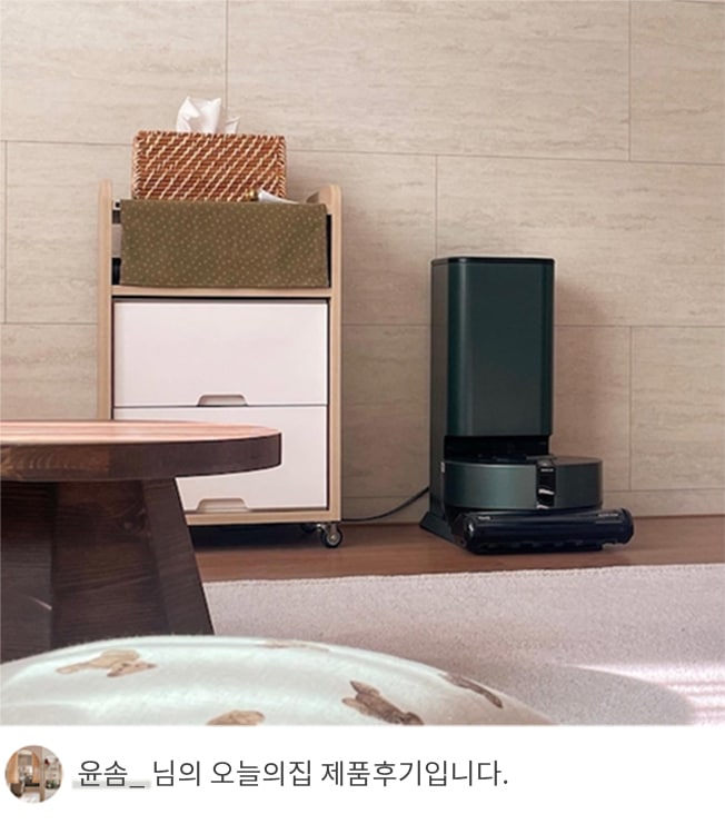 LG 코드제로 오브제컬렉션 R9 로봇청소기가 충전 거치대에 연결된 모습. 충전 거치대는 어두운 그린 컬러로 세련된 디자인을 갖추고 있으며, 옆에는 소품과 수납장이 배치되어 있습니다. 하단에는 '윤솜_ 님의 오늘의집 제품후기입니다.'라는 텍스트가 포함되어 사용자의 후기를 강조합니다.