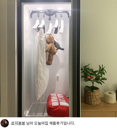 대체 텍스트: LG 스타일러 오브제컬렉션 내부에 걸려 있는 옷과 인형의 모습. 내부 조명이 켜져 있으며, 하단에 '로지봉봉 님의 오늘의집 제품후기입니다.'라는 텍스트가 포함되어 있음.