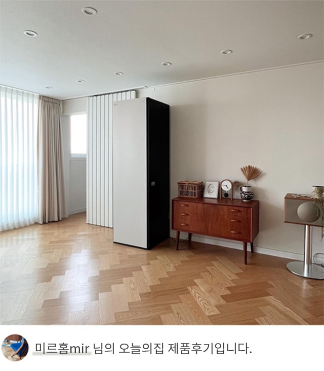 넓은 거실 공간에 LG 스타일러 오브제컬렉션이 원목 가구와 함께 배치된 모습. 하단에는 ‘미르홈mir 님의 오늘의집 제품후기입니다.’라는 텍스트가 포함되어 있음.