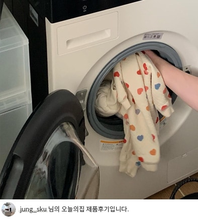 LG 트롬 오브제컬렉션 워시타워 컴팩트 세탁기에 손이 아기 옷을 넣고 있는 모습. 세탁기 문이 열려있어 내부 공간이 보이며, 아기 옷과 같은 작은 빨래도 매일 쉽게 세탁할 수 있는 기능을 강조합니다. 하단에는 'jung_sku 님의 오늘의집 제품후기입니다.'라는 텍스트가 포함되어 있습니다.