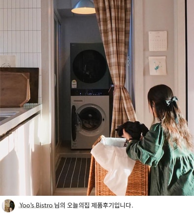 LG 트롬 오브제컬렉션 워시타워 컴팩트 앞에서 빨래 바구니를 들고 있는 사용자의 모습. 워시타워 주변에는 체크 패턴의 커튼과 따뜻한 조명이 배치되어 있으며, 하단에는 'Yoo's Bistro 님의 오늘의집 제품후기입니다.'라는 텍스트가 포함되어 있음.