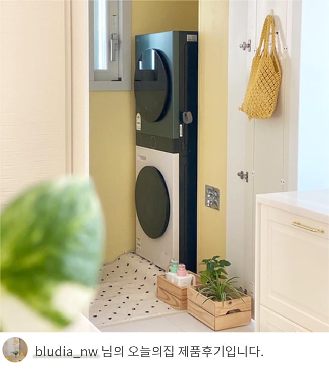 LG 트롬 오브제컬렉션 워시타워 컴팩트가 세탁실 안에 설치되어 있는 모습입니다. 공간 활용성을 강조한 제품으로 주변에는 화분과 세탁 액세서리가 배치되어 있습니다. 하단에는 'bludia_nw 님의 오늘의집 제품후기입니다.'라는 텍스트가 포함되어 있음.