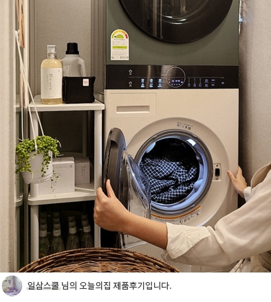 사용자가 LG 트롬 오브제컬렉션 워시타워 컴팩트의 세탁기 도어를 열고 세탁물을 넣는 모습입니다. 화면 하단에는 '일삼스쿨 님의 오늘의집 제품후기입니다.'라는 텍스트가 포함되어 있어, 제품 사용 후기에 대한 내용임을 알 수 있습니다.