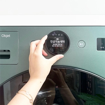 LG 트롬 오브제컬렉션 세탁건조기가 세탁실에 설치되어 있으며, 그린 컬러 포인트와 디테일한 기능 버튼이 실용성을 강조합니다.