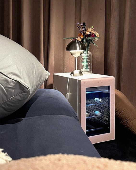 LG 디오스 오브제컬렉션 와인셀러가 거실에 배치되어 있으며, 위에는 조명과 꽃병이 놓여 있어 고급스럽고 아늑한 분위기를 연출하고 있습니다.