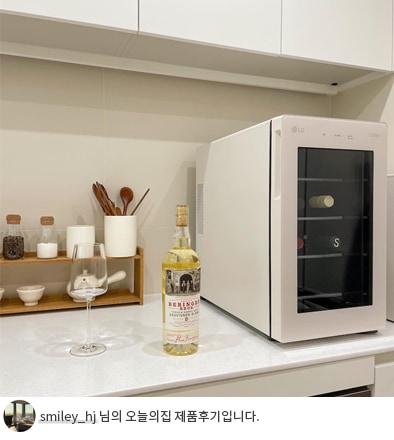 주방 조리대 위에 배치된 LG 디오스 오브제컬렉션 와인셀러와 와인 병의 모습이며, 'smiley_hj 님의 오늘의집 제품후기입니다.' 텍스트가 포함된 이미지.