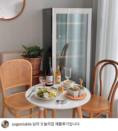 LG 디오스 오브제컬렉션 와인셀러가 식탁 옆에 놓여 있는 모습. 셀러 옆에는 나무 의자와 흰색 원형 테이블이 배치되어 있으며, 테이블 위에는 와인과 와인잔, 디저트와 과일이 놓여 있어 여유로운 브런치 분위기를 연출. 하단에는 'sogontable 님의 오늘의집 제품후기입니다.'라는 텍스트가 포함되어 있음.