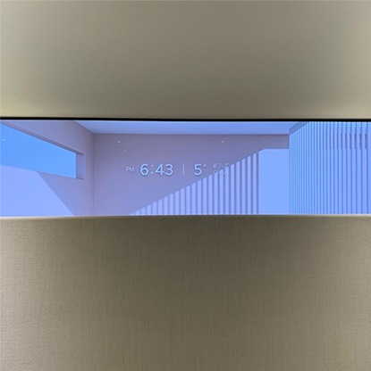 LG 올레드 오브제컬렉션 Easel TV의 디스플레이 상단 모습으로, 디스플레이에 시계와 날씨 정보가 표시되고 있음. TV의 슬림한 디자인과 세련된 디테일이 강조되어 미니멀한 인테리어와 잘 어우러짐.