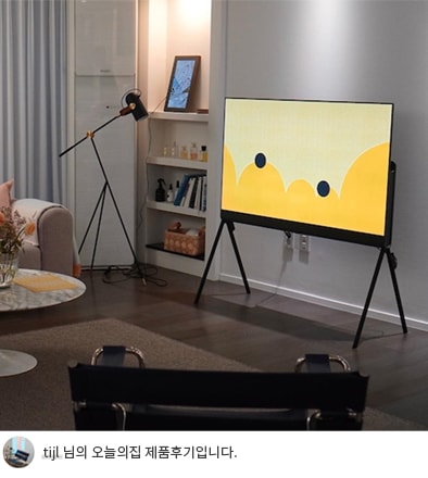 LG 올레드 오브제컬렉션 Posé TV가 밝은 노란색 화면을 표시하고 있는 모습. TV 뒤에는 책장과 스탠드 조명이 배치되어 있으며, 하단에는 'tijl 님의 오늘의집 제품후기입니다.'라는 텍스트가 포함되어 있음.