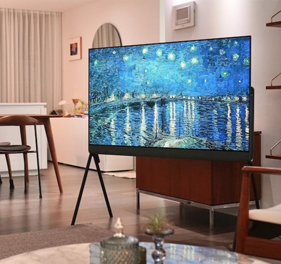 밝은 거실에 설치된 LG 올레드 오브제컬렉션 Posé TV가 벽화처럼 생생한 예술 작품 이미지를 표시하고 있는 모습. 주변에는 테이블과 의자가 배치되어 아늑한 인테리어를 연출함