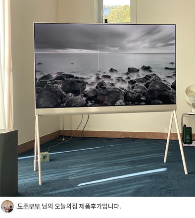 고급스러운 실내 공간에 LG 올레드 오브제컬렉션 포제(Posé) TV가 설치되어 있으며, 화면에는 흑백 풍경 사진이 표시되어 있습니다. 하단에는 '도주부부 님의 오늘의집 제품후기입니다.'라는 텍스트가 포함되어 있습니다.