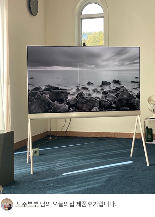 고급스러운 실내 공간에 LG 올레드 오브제컬렉션 포제(Posé) TV가 설치되어 있으며, 화면에는 흑백 풍경 사진이 표시되어 있습니다. 하단에는 '도주부부 님의 오늘의집 제품후기입니다.'라는 텍스트가 포함되어 있습니다.