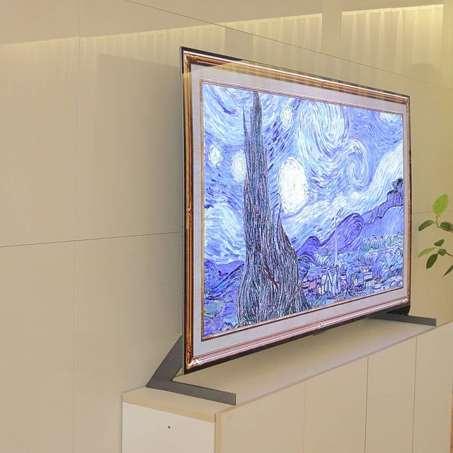TV가 거실 벽에 설치되어 있음. 화면에는 반 고흐의 별이 빛나는 밤 그림이 표시되어 있으며, 옆에는 녹색 식물이 일부 보임.