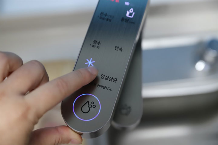 손가락으로 LG 정수기의 상단 조작부에서 '안심 살균' 기능을 선택하는 모습
