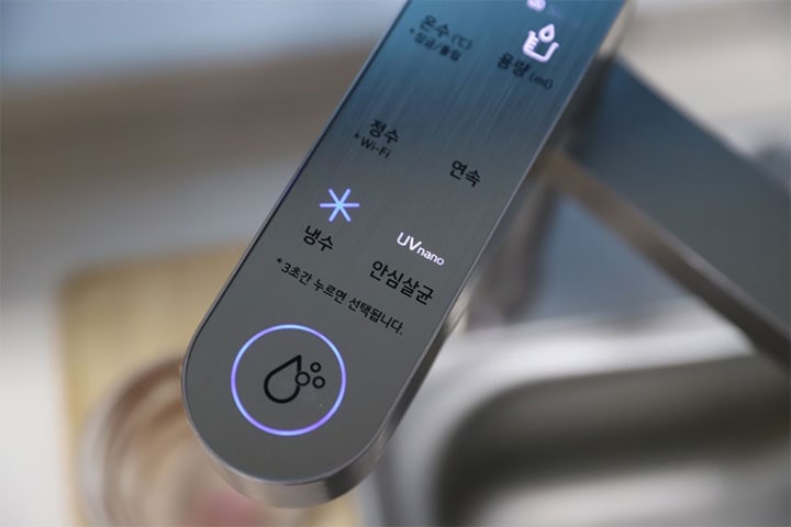 LG 퓨리케어 정수기의 상단 조작부 클로즈업 이미지로, 냉수와 'UV 나노 안심 살균' 기능이 표시되어 있으며, 버튼에 파란색 조명이 들어와 있는 모습