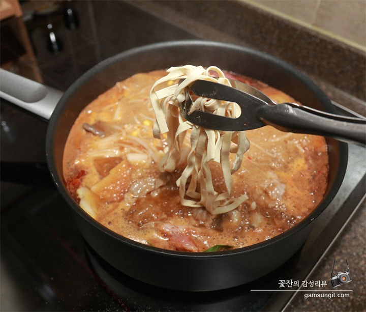 LG 디오스 인덕션 위에 놓인 냄비에서 마라탕이 끓고 있으며, 집게로 익은 면을 건져 올리는 모습