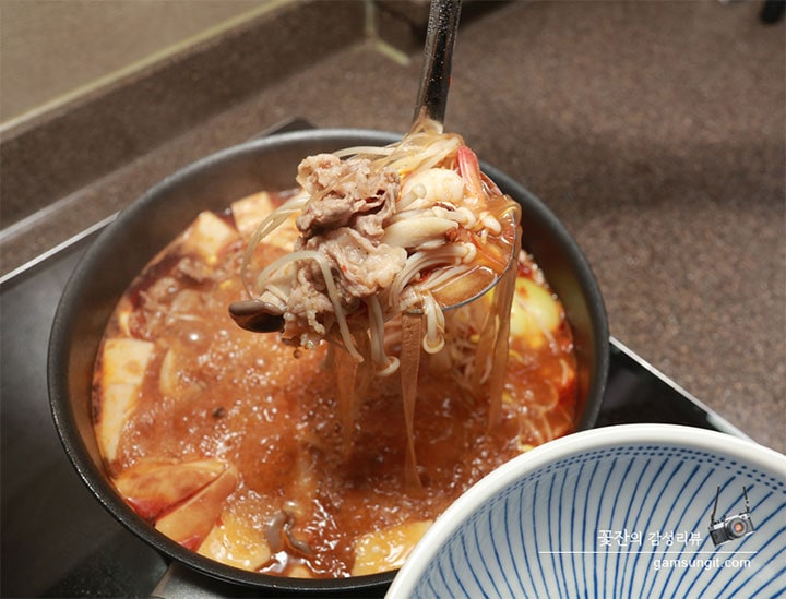 LG 디오스 인덕션 위에서 마라탕이 끓고 있으며, 국자에 고기와 숙주, 버섯 등을 듬뿍 떠서 그릇에 담으려는 모습