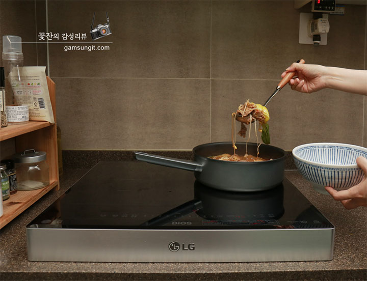 주방에서 LG 디오스 인덕션 위에 놓인 냄비에서 마라탕을 국자로 떠 그릇에 담고 있는 모습