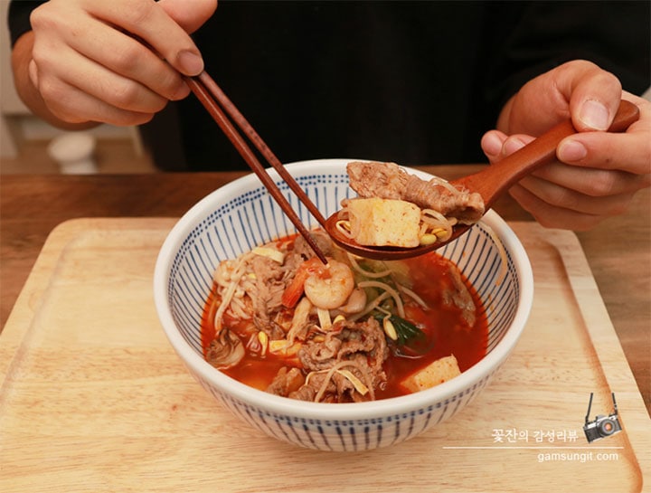 완성된 마라탕 요리가 그릇에 담겨 있으며, 젓가락으로 고기와 재료를 들어 올리는 모습