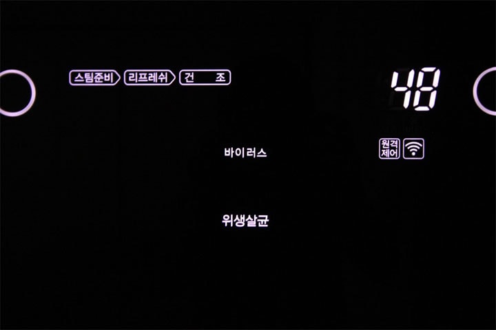 어두운 배경에서 LG 스타일러의 디지털 패널이 밝게 표시된 모습으로, '바이러스'와 '위생살균' 코스가 선택된 상태이며, 설정 시간이 48분으로 나타나 있음
