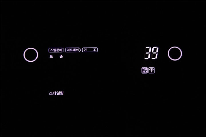 어두운 배경에서 LG 스타일러의 디지털 패널이 밝게 표시된 화면으로, '스타일링' 코스가 선택되어 있으며 설정 시간이 39분으로 나타나 있음