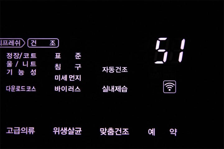 어두운 배경에서 LG 스타일러의 디지털 패널이 밝게 표시된 화면으로, '맞춤건조' 코스가 선택되어 있으며 설정 시간이 51분으로 나타나 있음