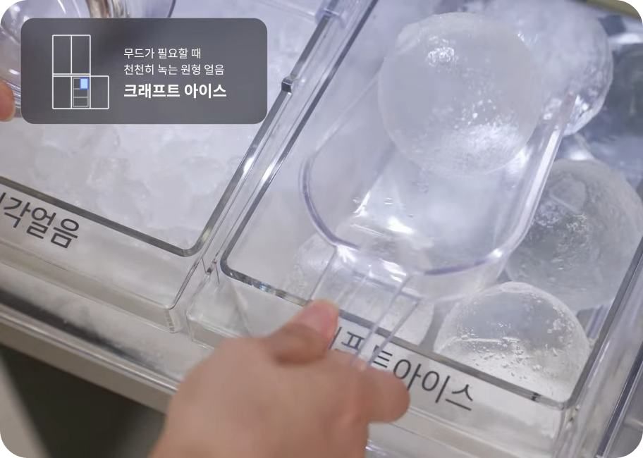 냉동실 얼음 통에서 투명하고 둥근 원형 얼음을 전용 스쿱으로 떠내고 있는 모습입니다. 이미지 상단에는 