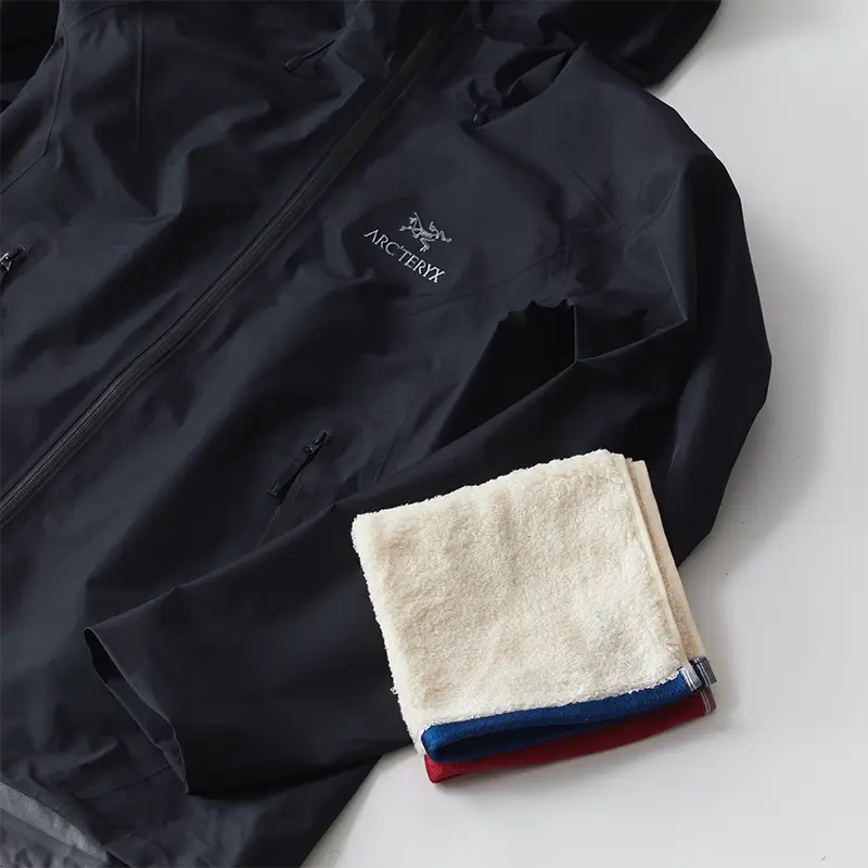 야외 활동 후 마른 수건과 젖은 수건으로 윈드브레이커 겉면의 먼지와 흙을 닦아내는 바람막이 관리 이미지