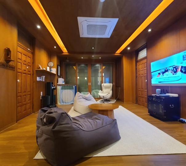 시스템에어컨, 빈팩, 테이블 TV등이 있는 우드톤의 거실