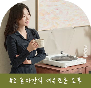 레코드 플레이어 옆에서 커피를 들고 여유로운 오후를 보내는 여성의 모습. 배경에는 예술적인 그림이 걸려 있어 차분한 분위기를 자아낸다. 이미지 하단에는 '#2 혼자만의 여유로운 오후'라는 텍스트가 포함되어 있다.