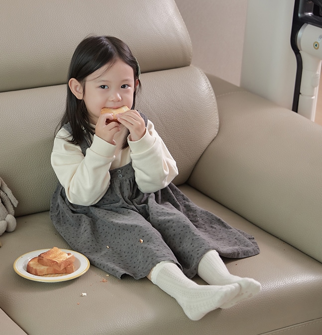 쇼파에서 과자를 먹고 있는 아이.