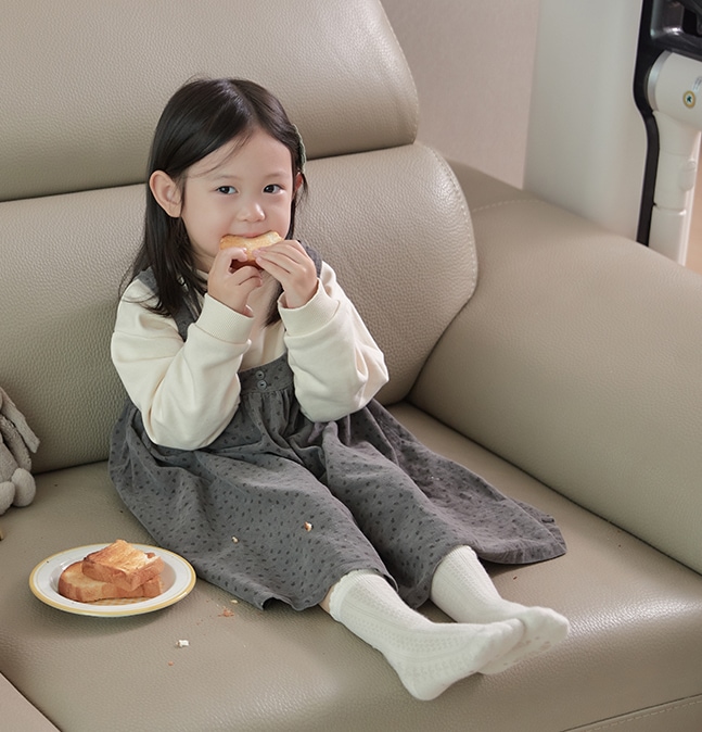 소파에 앉아 아침 식사로 토스트를 먹고 있는 어린 소녀의 모습. 옆에 LG 코드제로 A9S 오브제컬렉션이 배치되어 있음.