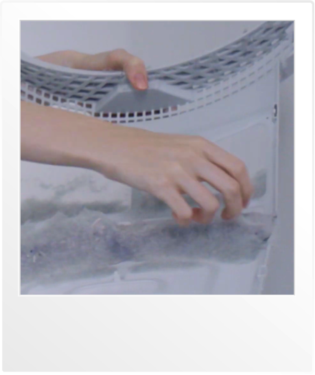 건조기의 필터에서 먼지를 제거하는 손의 클로즈업 이미지. 필터에 쌓인 먼지를 손으로 떼어내는 모습이 보이며, 깨끗한 건조기를 유지하는 과정을 보여줍니다.