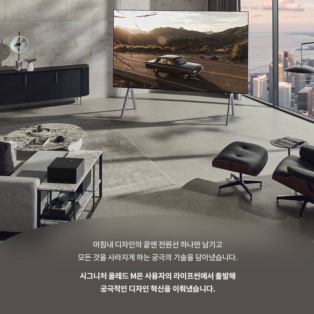 거실에 배치된 LG 시그니처 올레드 M TV와 그 앞에 위치한 원형 테이블, 편안한 의자들이 함께 어우러진 실내 공간. TV 화면에는 석양이 드리워진 도로와 자동차가 나타나며, 뒤로 도시와 자연 풍경이 보인다. 하단 텍스트는 제품의 미니멀리즘과 혁신적 디자인에 대해 설명한다.