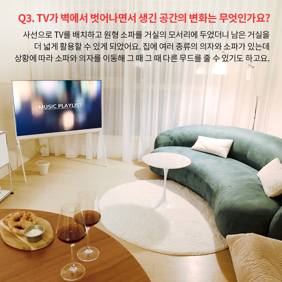 밝은 거실에 Music Playlist라는 텍스트가 표시된 올레드 TV가 배치되어 있으며, 둥근 소파와 화이트 테이블이 조화를 이루는 모습. TV를 벽이 아닌 독립형으로 배치하여 공간을 더 효율적으로 활용할 수 있음을 보여줍니다. 주된 내용은 가구 배치의 자유로움과 TV 배치 변화가 공간 분위기를 어떻게 개선하는지를 설명합니다.
