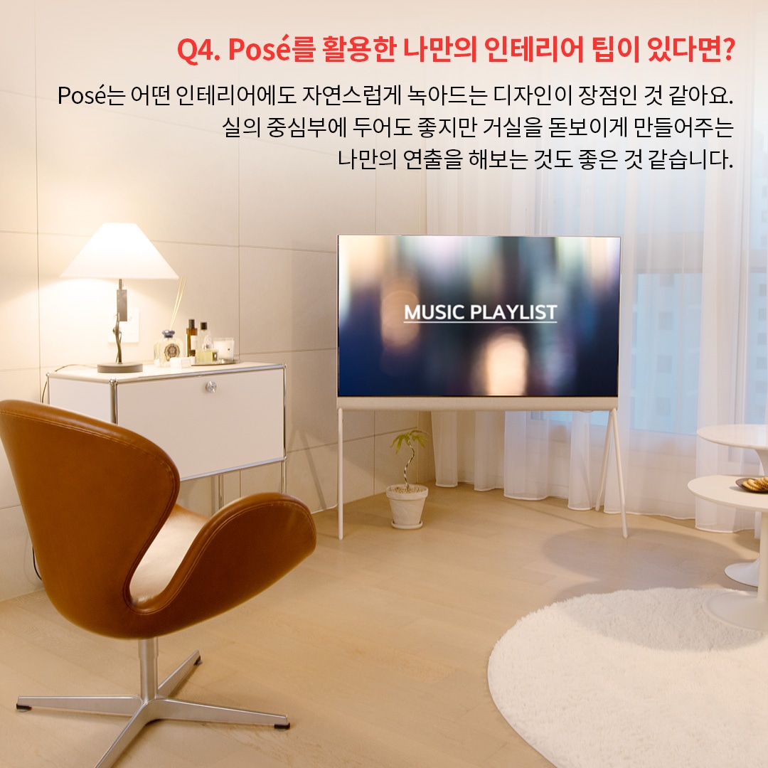 올레드 TV가 거실 중앙에 놓여 있고 Music Playlist 화면이 표시되어 있으며, 옆에는 갈색의 의자와 화이트 테이블이 조화를 이루고 있습니다. Posé TV를 활용하여 거실의 중심부를 연출하면서도 자연스럽게 공간과 어우러지도록 배치한 사례를 보여줍니다.