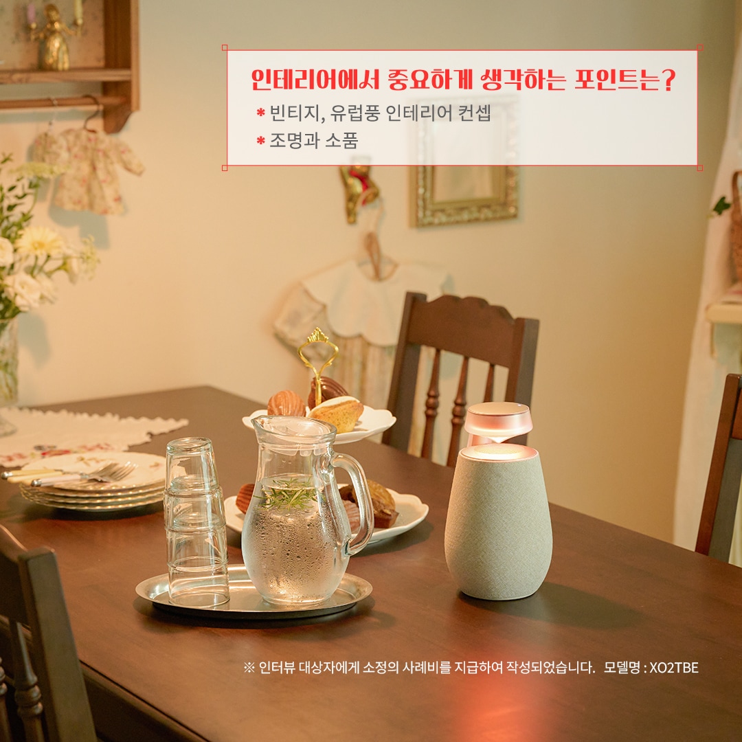 인테리어에서 중요하게 생각하는 포인트는? 빈티지, 유럽풍 인테리어 콘셉 조명과 소품 ※ 인터뷰 대상자에게 소정의 사례비를 지급하여 작성되었습니다. 모델명: XO2TBE 문구 표시됨. 배경은 우드톤 식탁 위에 유럽풍 티 세트와 디저트가 놓여 있음. 벽에는 빈티지 소품과 장식이 배치되어 따뜻한 분위기를 연출하며, 블루투스 스피커가 감성을 더함.