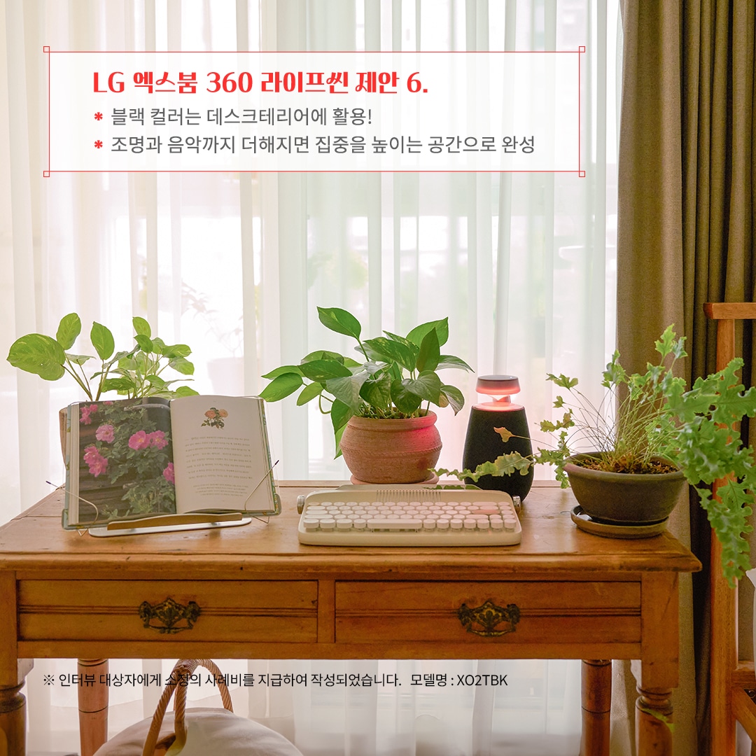 LG 엑스붐 360 라이프셋 제안 6. 블랙 컬러는 데스크테리어에 활용! 조명과 음악까지 더해지면 집중을 높이는 공간으로 완성 ※ 인터뷰 대상자에게 소정의 사례비를 지급하여 작성되었습니다. 모델명: XO2TBK 문구 표시됨. 배경은 우드 책상 위에 키보드, 오픈된 책, 블루투스 스피커, 여러 개의 화분이 놓여 있음. 배경에는 커튼과 창문이 있으며, 자연광이 들어와 따뜻하고 조용한 분위기를 연출함.