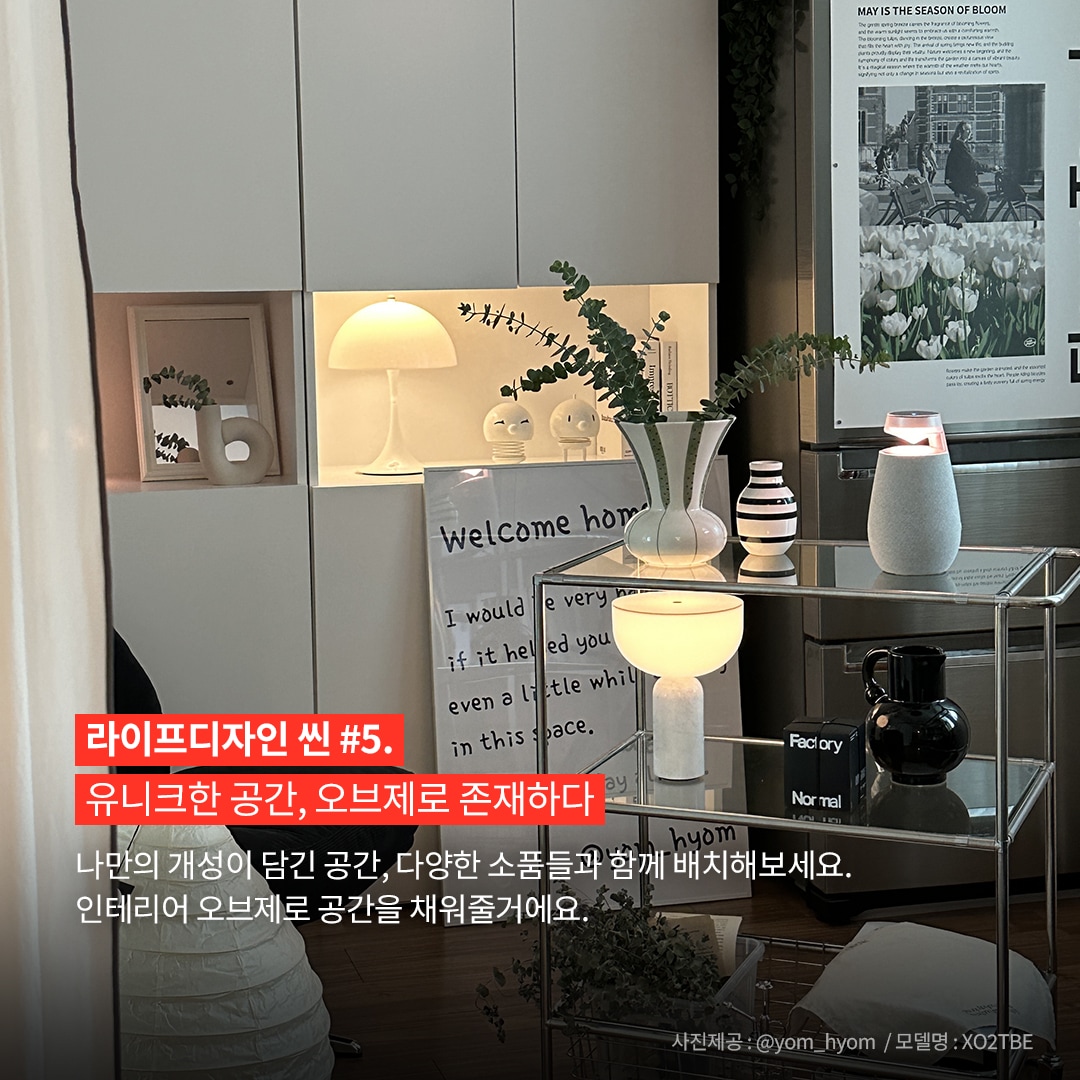 라이프디자인 씬 5. 유니크한 공간, 오브제로 존재하다 나만의 개성이 담긴 공간, 다양한 소품들과 함께 배치해보세요. 인테리어 오브제로 공간을 채워줄 거예요. 사진제공: @yom.hyom / 모델명: XO2TBE 문구 표시됨. 배경은 현대적인 인테리어로 꾸며진 방에는 흰색 선반과 유리 테이블이 있으며, 선반에는 다양한 장식품과 식물이 배치. 유리 테이블 위에는 엑스붐 360 스피커와 모던한 액세서리들이 놓여 있음.