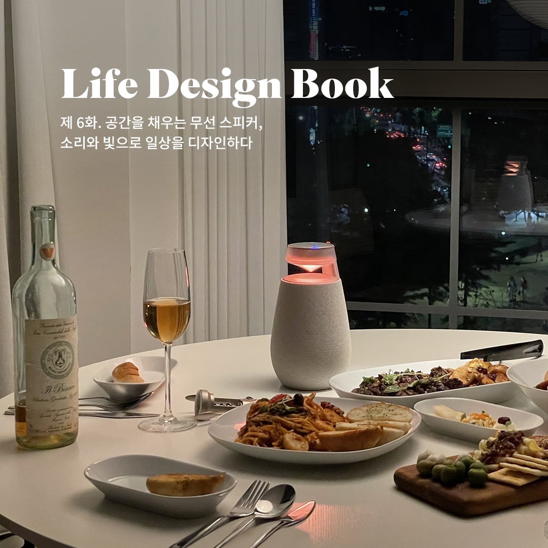 Life Design Book 제 6화. 공간을 채우는 무선 스피커, 소리와 빛으로 일상을 디자인하다 문구 표시됨. 배경은 원형 흰색 테이블 중앙에는 조명이 켜진 엑스붐 360 스피커가 놓여 있음. 창문 너머로 도시의 야경이 보이며, 테이블 위에는 와인 한 병과 와인잔, 다양한 음식이 차려진 접시들이 있음.