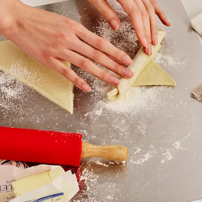 크루아상 반죽을 삼각형으로 성형하는 장면 