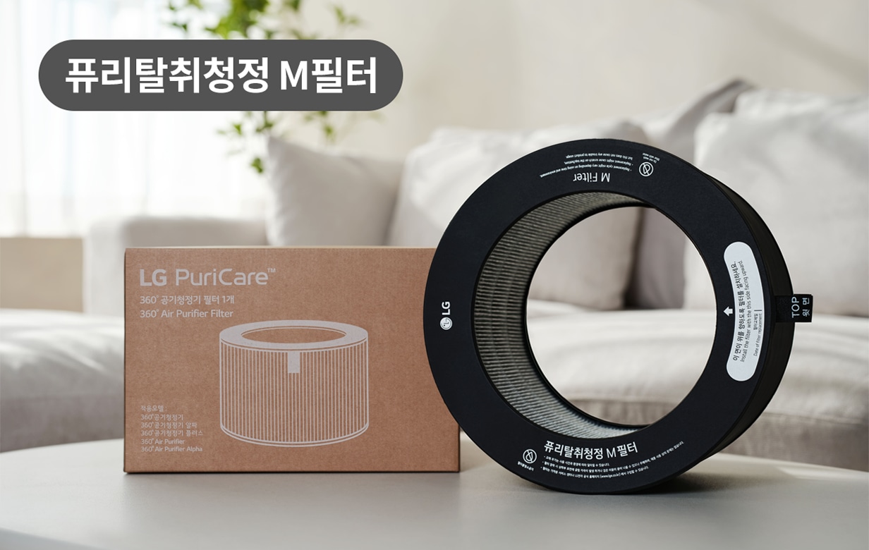 LG PuriCare 360° 공기청정기의 교체용 필터와 포장 박스가 소파 위에 배치된 모습. 필터는 원형 구조로 내부의 필터망이 보이며, 박스에는 제품명이 인쇄되어 있음.