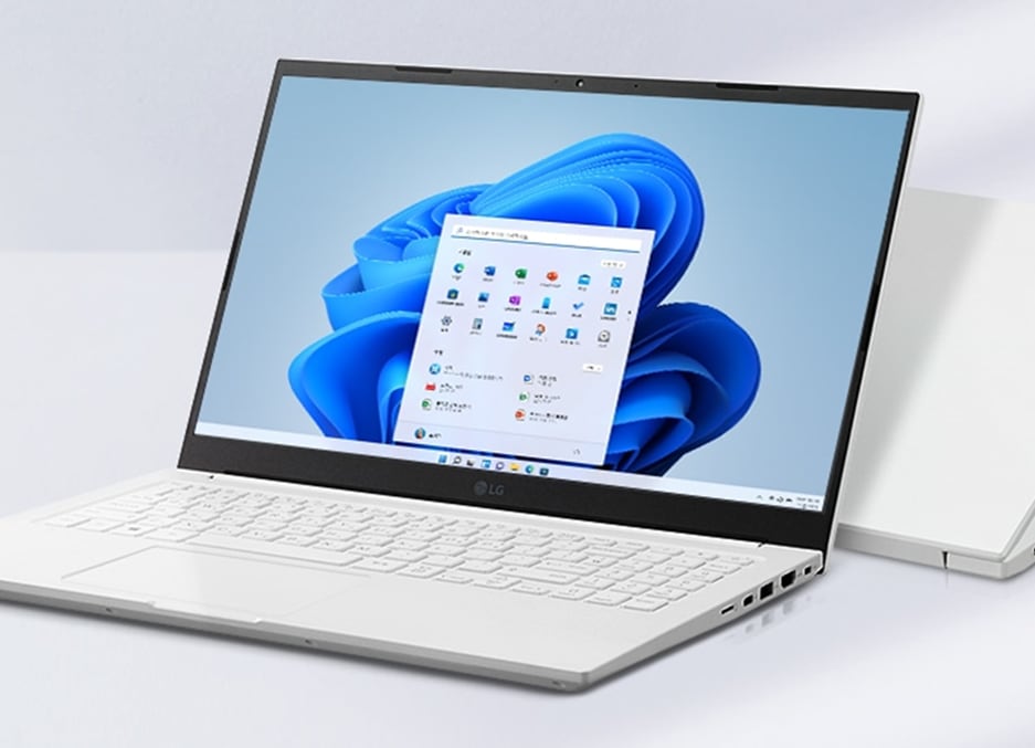 LG 그램 노트북이 열려 있으며, 화면에는 윈도우 11 바탕화면과 시작 메뉴가 표시되어 있습니다. 노트북은 흰색 키보드와 슬림한 디자인을 가지고 있으며, 배경에는 닫힌 상태의 LG 그램이 놓여 있습니다.