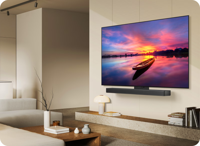 거실 벽에 LG 올레드 TV가 설치되어 있으며, TV 화면에는 노을이 지는 호수 위에 나룻배가 떠 있는 풍경이 선명하게 표시된 모습.