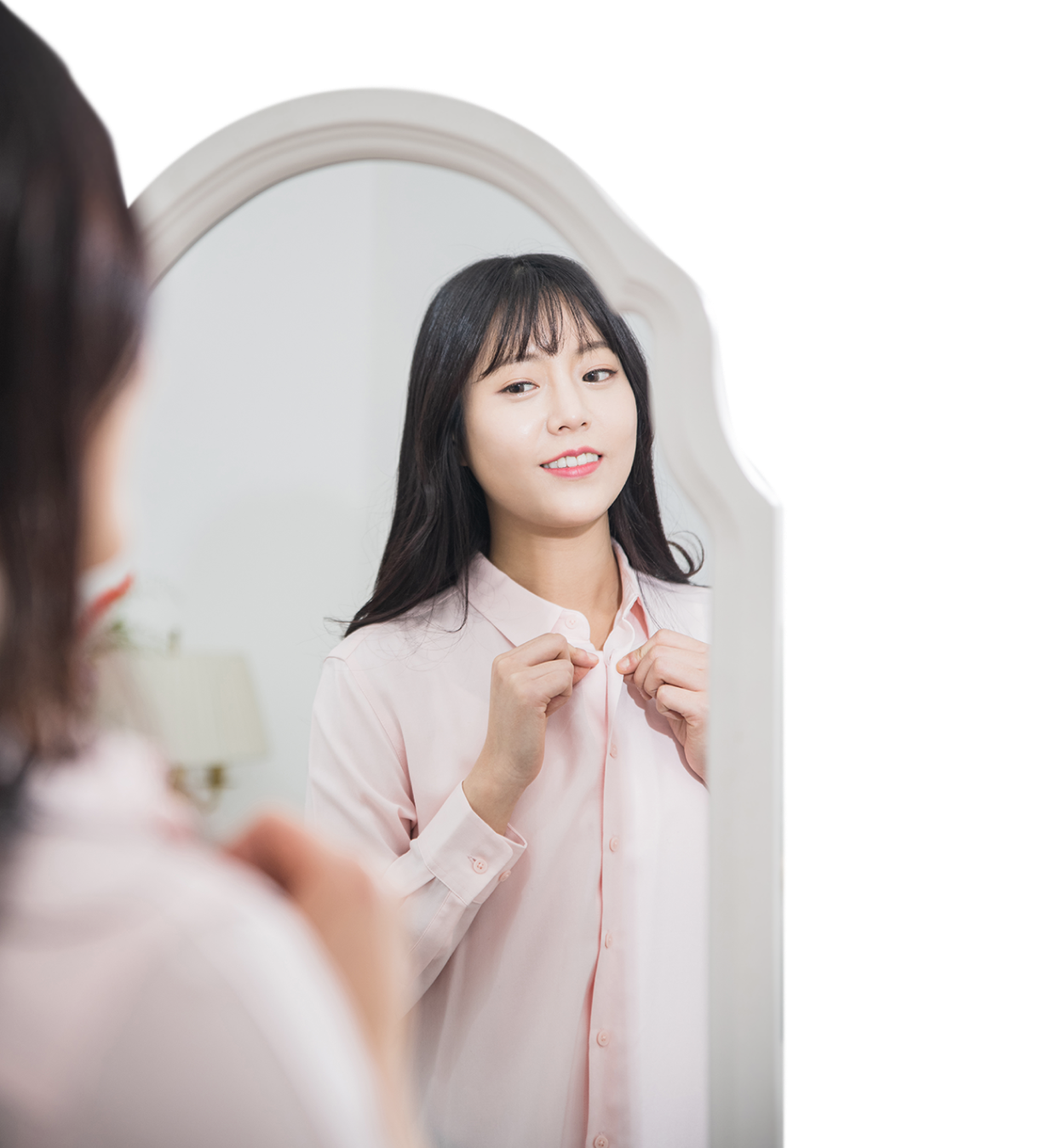 거울을 보며 면 셔츠를 입고 있는 사람 모습.