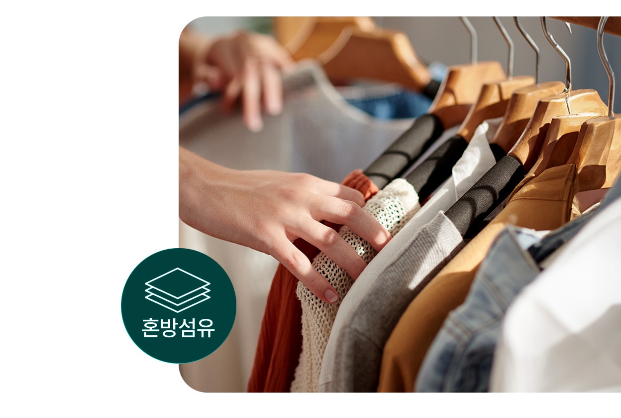 옷걸이에 걸린 다양한 의류를 손으로 고르는 모습으로, 좌측 하단에는 혼방섬유 아이콘이 표시되어 있는 모습.