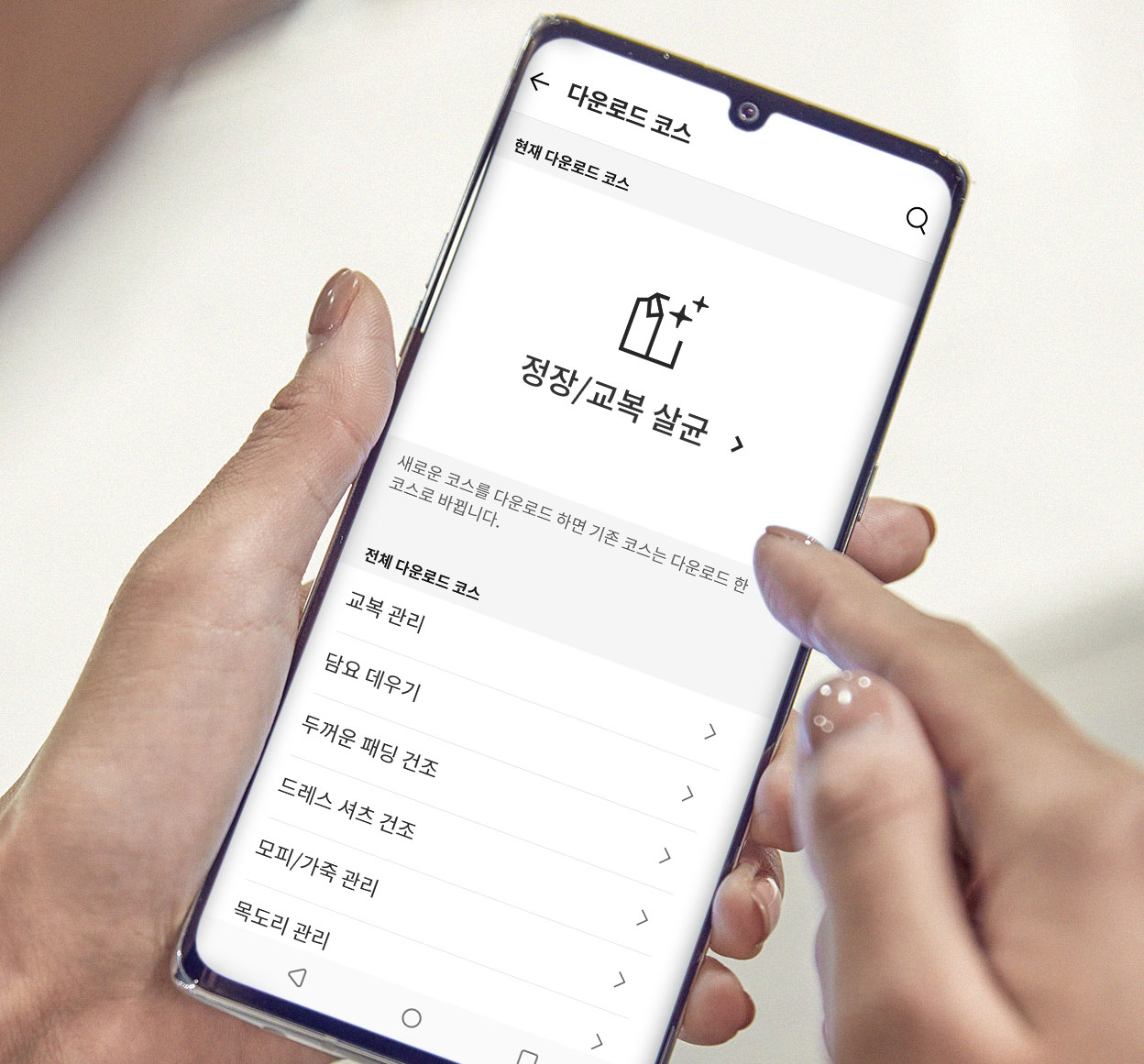 스마트폰을 이용해 스타일러 관리 애플리케이션에서 다양한 세탁 및 건조 코스를 다운로드하는 모습